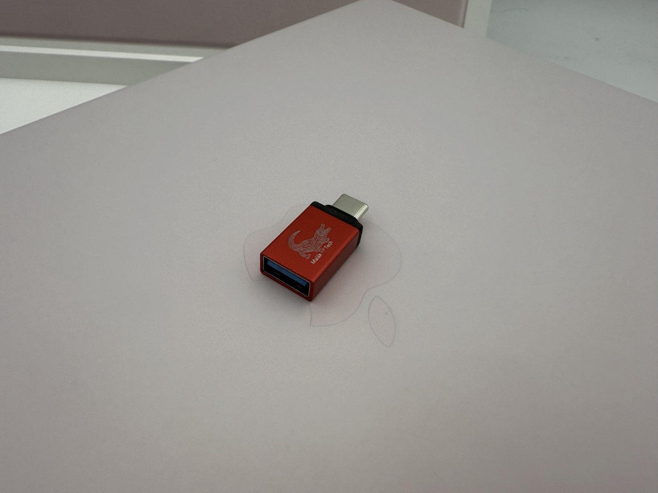 Piros, Malák Tech logós USB-C – USB-A átalakító egy MacBook fedelén – amit az Apple nem ad a géphez